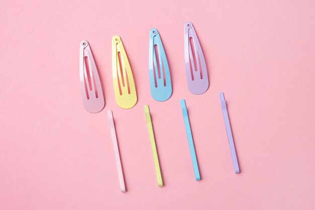 Grupa kolorowych pastelowych spinek do włosów na różowym tle, stylizowany strzał, nowoczesne akcesoria do włosów widok z góry