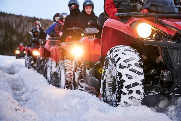 Grupa ludzi jeżdżących quadami po zaśnieżonej drodze