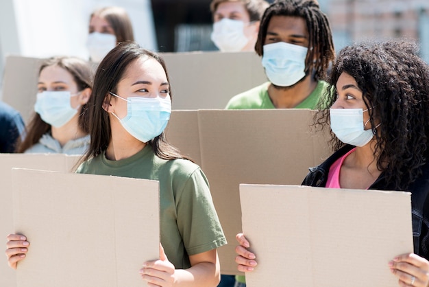 Bezpłatne zdjęcie grupa ludzi protestujących i noszących maski medyczne
