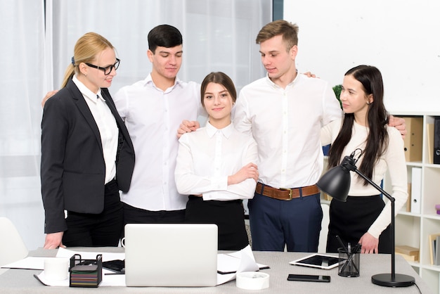 Grupa ludzie biznesu patrzeje jego żeńskiej kolega pozycję za biurkiem w biurze