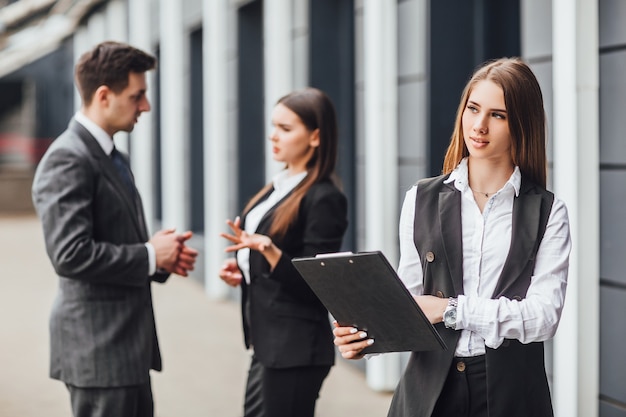 Grupa partnerów biznesowych planuje pracę z naciskiem na uśmiechniętą kobietę z folderem!