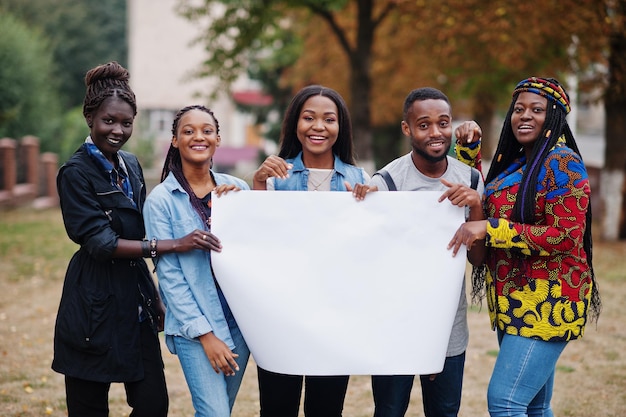 Grupa pięciu afrykańskich studentów na kampusie na uniwersyteckim dziedzińcu przytrzymaj puste białe puste miejsce na tekst Czarni afro przyjaciele studiują