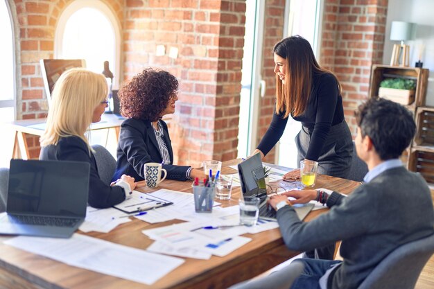 Grupa pracowników biznesowych uśmiecha się szczęśliwy i pewny siebie Praca razem z uśmiechem na twarzy M?oda pi?kna kobieta, stoj?ca, wyja?niaj?c dokumenty w biurze