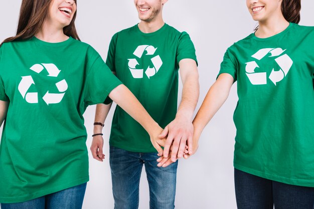 Grupa przyjaciele układa ich ręki w zielonej koszulce