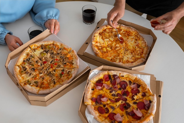 Bezpłatne zdjęcie grupa przyjaciół jedzących razem pizzę w domu