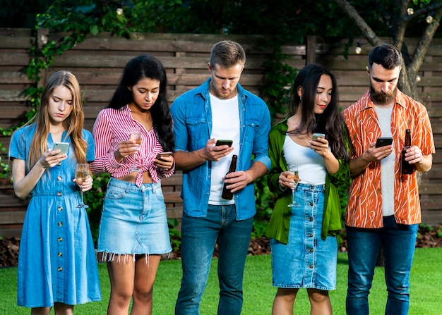 Bezpłatne zdjęcie grupa przyjaciół ze smartfonami na zewnątrz