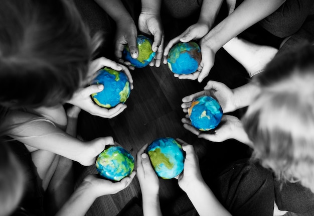 Grupa różnorodni dzieciaki wręcza trzymać cupping kul ziemskich piłki wpólnie