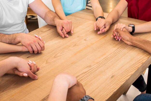 Grupa różnorodni ludzie trzyma ręki na drewnianym biurku