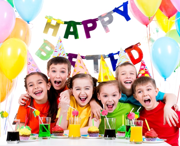 Grupa śmiejących się dzieci zabawy na przyjęciu urodzinowym - na białym tle.
