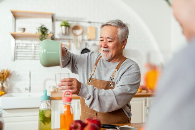 Grupa starszych przyjaciół posiadających imprezę w pomieszczeniu, gotowanie i rozmawianie pozytywnej rozmowy w starszym daycareasian Starszy mężczyzna stojący w kuchni i relaksujący się w domu podczas jedzenia zdrowego przepisu na żywność