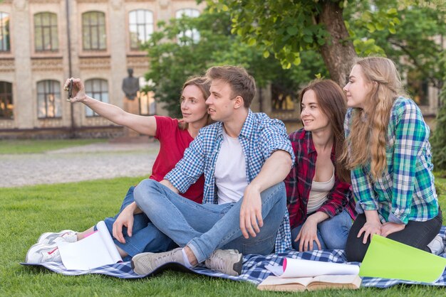 Grupa studentów siedzi obok drzewa