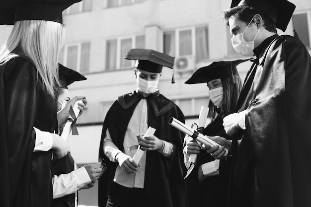 Bezpłatne zdjęcie grupa studentów wspólnie świętujących ukończenie szkoły i noszących maski na twarz