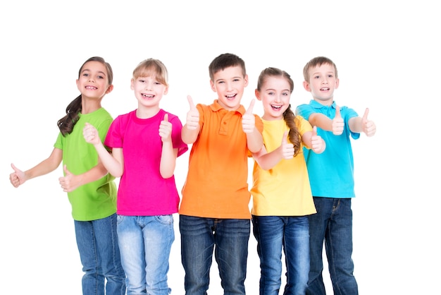 Bezpłatne zdjęcie grupa szczęśliwych dzieciaków z kciukiem do góry podpisania w kolorowe t-shirty stojące razem - na białym tle.
