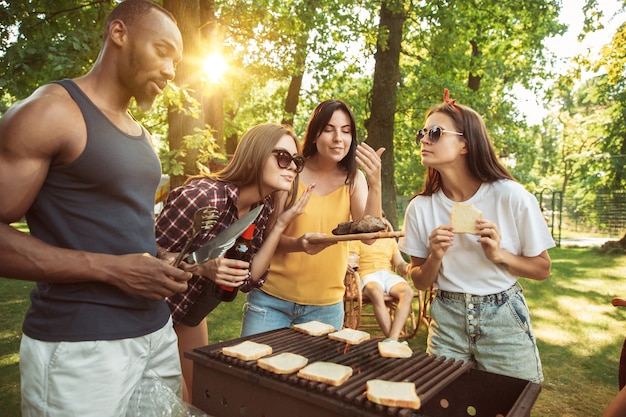 Grupa szczęśliwych przyjaciół o piwo i grill party w słoneczny dzień.