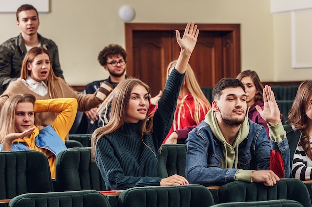 Bezpłatne zdjęcie grupa wesołych, szczęśliwych studentów siedzących w sali wykładowej przed lekcją