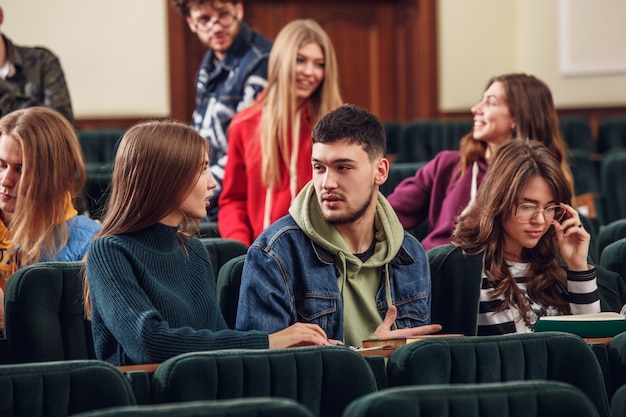 Bezpłatne zdjęcie grupa wesołych, szczęśliwych studentów siedzących w sali wykładowej przed lekcją