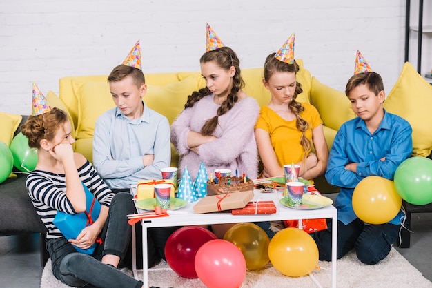 Grupa znudzeni przyjaciele siedzi w przyjęciu urodzinowym