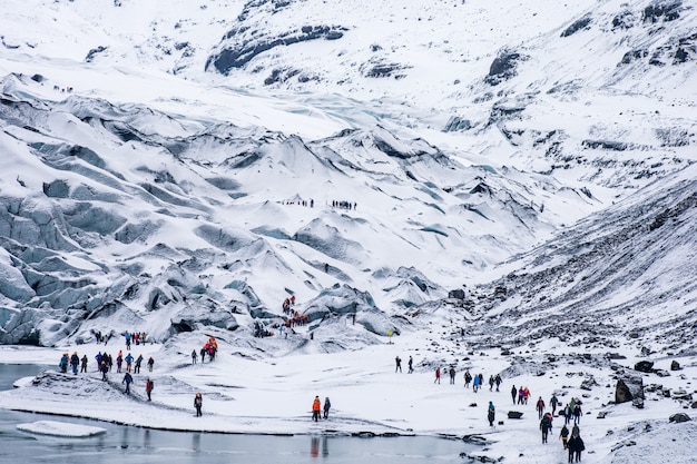 Grupy turystów pieszych wędrujących po śnieżnych, białych, surowych górach