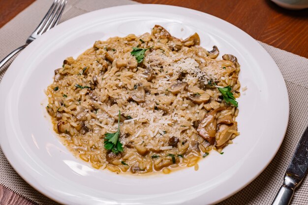 Grzybowe risotto przyozdobione tartym parmezanem i natką pietruszki