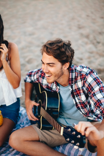 Bezpłatne zdjęcie guy gra na gitarze na plaży