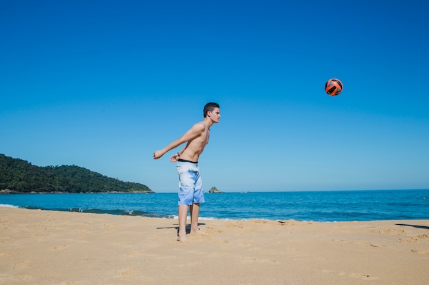 Bezpłatne zdjęcie guy gra w siatkówkę na plaży