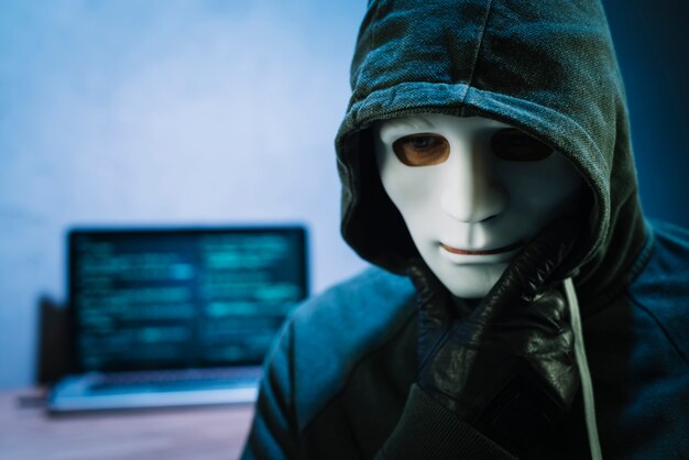Hacker z maską przed laptopem