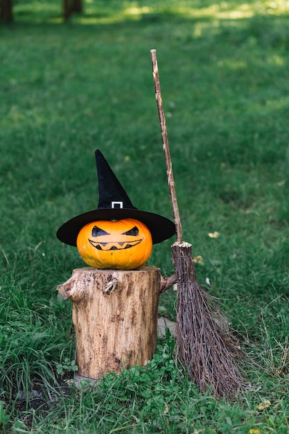 Bezpłatne zdjęcie halloweenowa bania z kapeluszem na fiszorku blisko broomstick