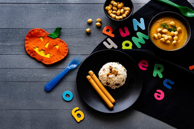 Halloweenowe jedzenie dla dzieci z dyniowym risotto i frankfurterkami, tapeta w tle