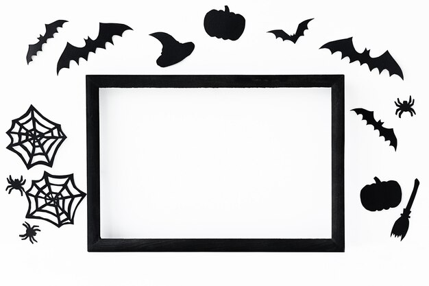 Halloweenowe tło z czarną ramką i czarnymi papierowymi akcesoriami na wakacje na szarej powierzchni