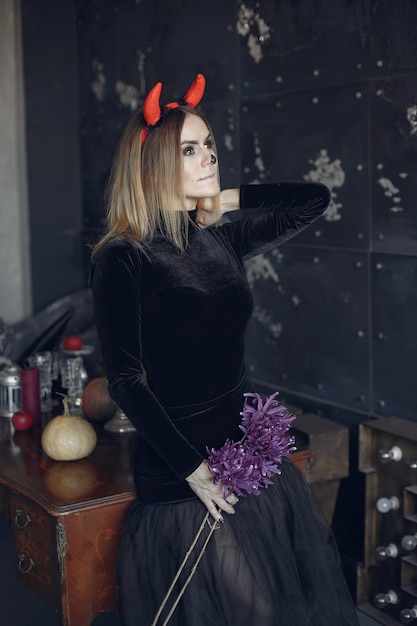 Halloweenowy makijaż piękna kobieta z blond fryzurą. Modelka dziewczyna w czarnym stroju. Motyw Halloween.