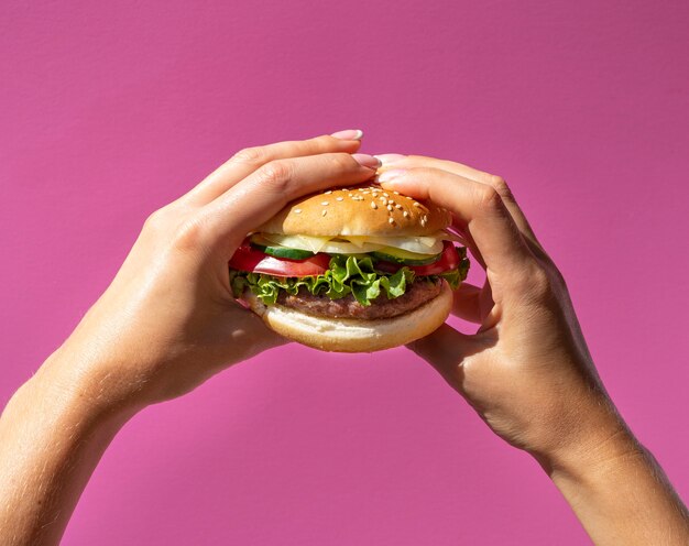 Hamburger trzymający przed purpurowym tłem
