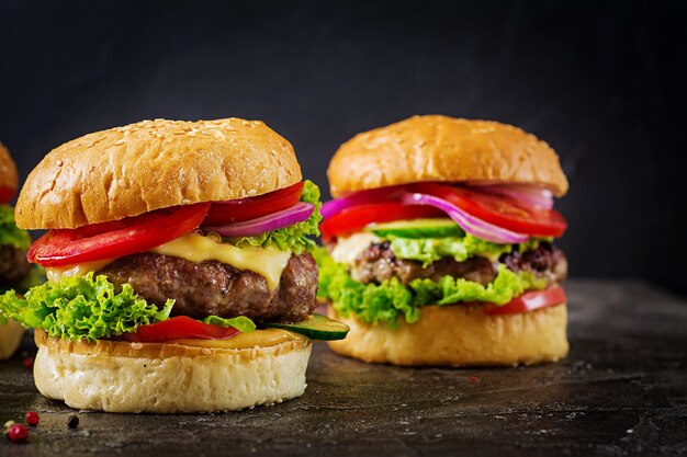 Hamburger z mięsem wołowym i świeżymi warzywami na ciemnej powierzchni.