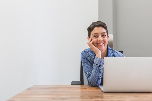 Bezpłatne zdjęcie happy businesswoman stwarzających obok jej laptopa