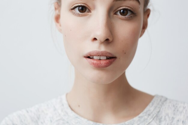 Headshot pięknej, uroczej młodej kobiety wyglądającej z lekko rozchylonymi ustami