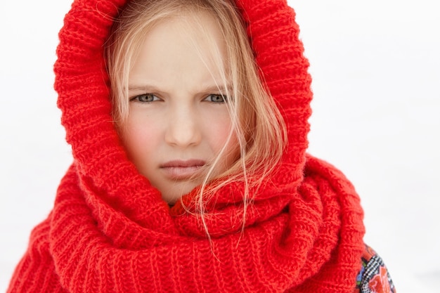 Headshot z piękną blondynką kaukaską małą dziewczynką ubrana w czerwony wełniany szalik wokół głowy i szyi