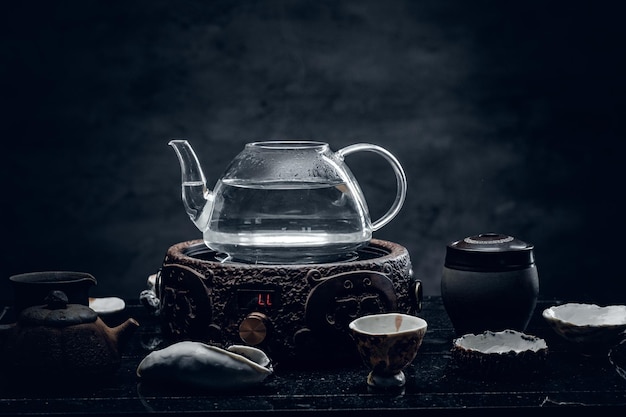 Herbaciana Ceremonia. Szklany przezroczysty czajniczek i egzotyczne ceramiczne kubki.