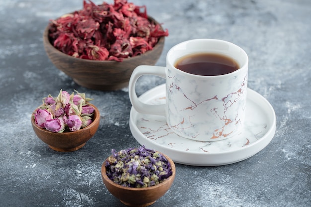 Herbata i suszone kwiaty na marmurowym stole.