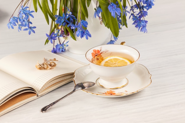 Herbata z cytryną i bukietem niebieskich pierwiosnek na stole