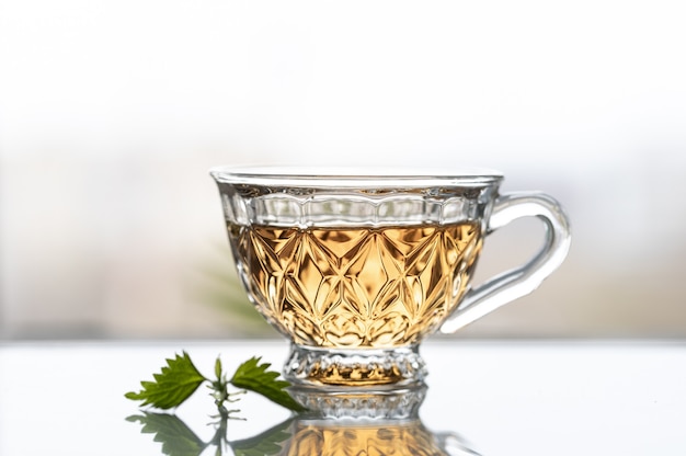 Bezpłatne zdjęcie herbata z młodych liści pokrzywy na tle okna. skopiuj miejsce