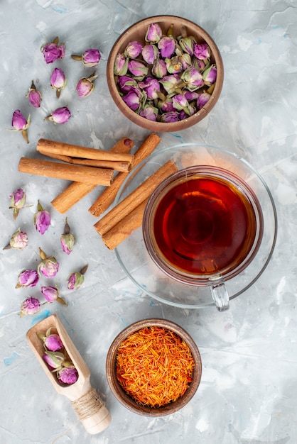 Bezpłatne zdjęcie herbata z widokiem z góry z cynamonem i fioletowym kwiatem na lekkim biurku