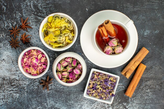 herbata ziołowa z laskami cynamonu i suszonymi kwiatami oraz anyżem na szaro