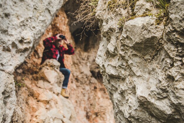 Hiker siedzi na skały przy użyciu lornetki