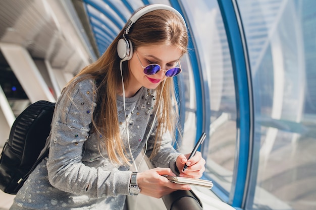 Bezpłatne zdjęcie hipster młoda kobieta w strój casual, zabawy, słuchanie muzyki w słuchawkach