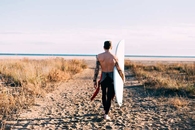 Hipster modny surfer na plaży z deską surfingową