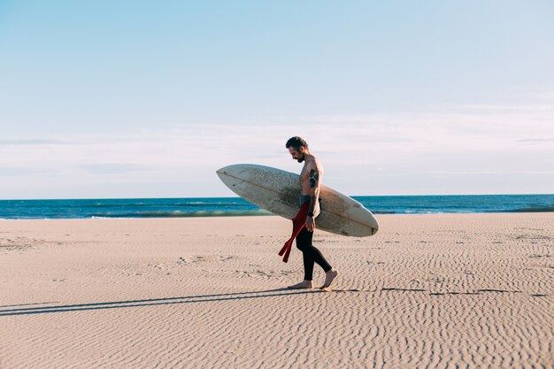 Hipster modny surfer na plaży z deską surfingową