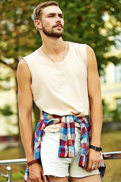 Bezpłatne zdjęcie hipster przystojny mężczyzna facet w stylowe letnie ubrania pozowanie na ulicy