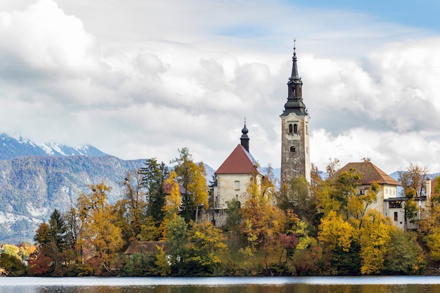 Historyczny kasztel otaczający zielonymi drzewami blisko jeziora pod białymi chmurami w Krwawiący, Slovenia