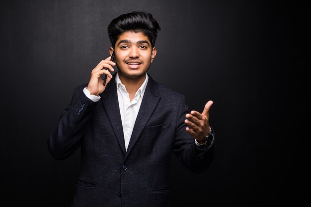 Indiański biznesowy mężczyzna opowiada na telefonie na czerni ścianie