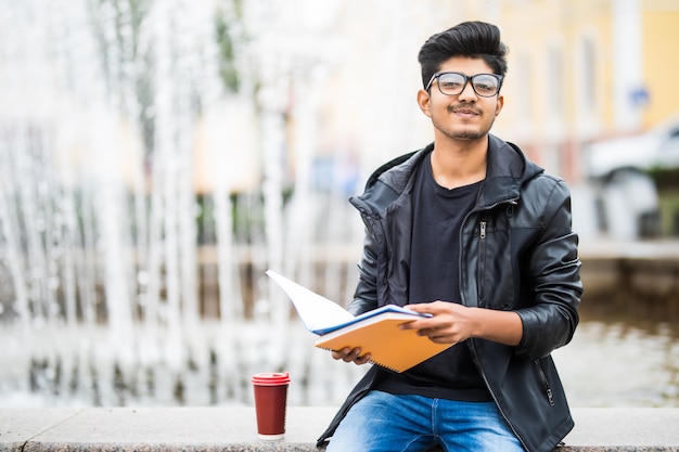 Indiański Studencki Mężczyzna Trzyma Stos Książki Siedzi Blisko Fontanny Na Ulicie