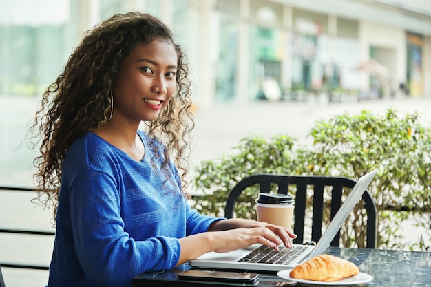 Indonezyjski bizneswoman używa laptop i patrzejący kamerę